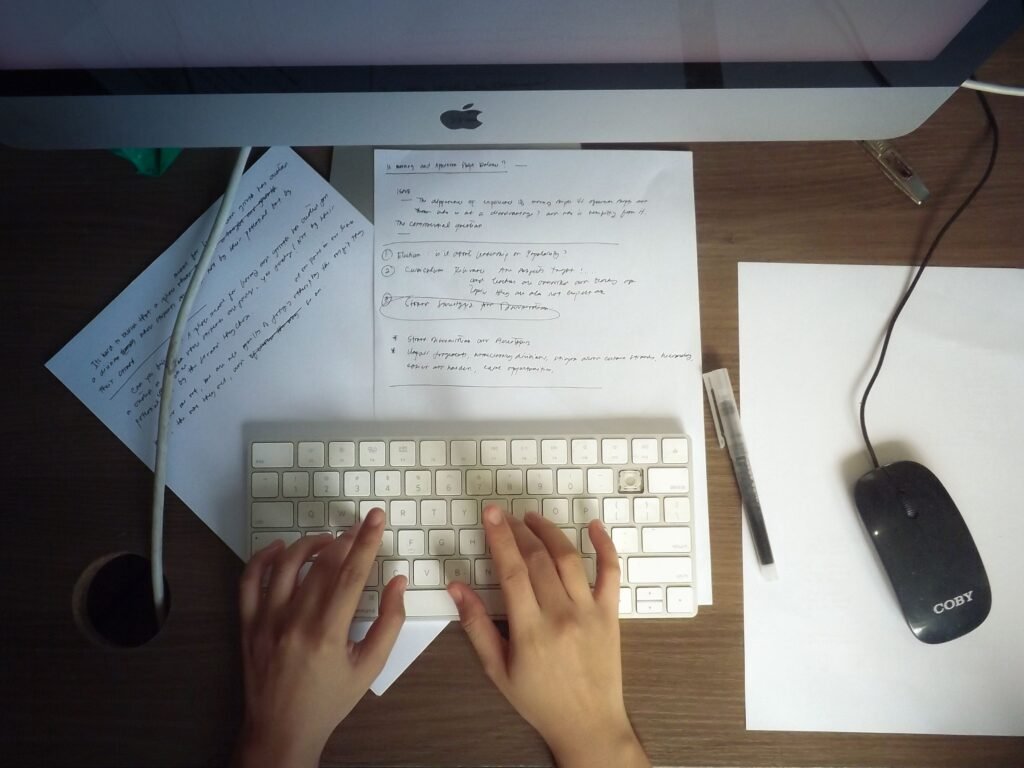 person working on computer with notes
